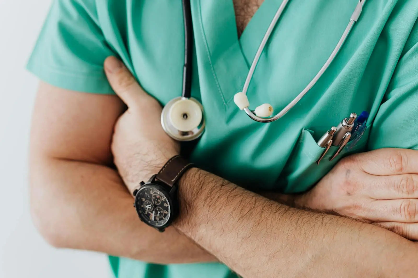 Doctor in scrubs with folded arms and stethoscope, symbolizing confidence in healthcare.