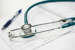 A stethoscope and pen resting on a medical report in a healthcare setting.