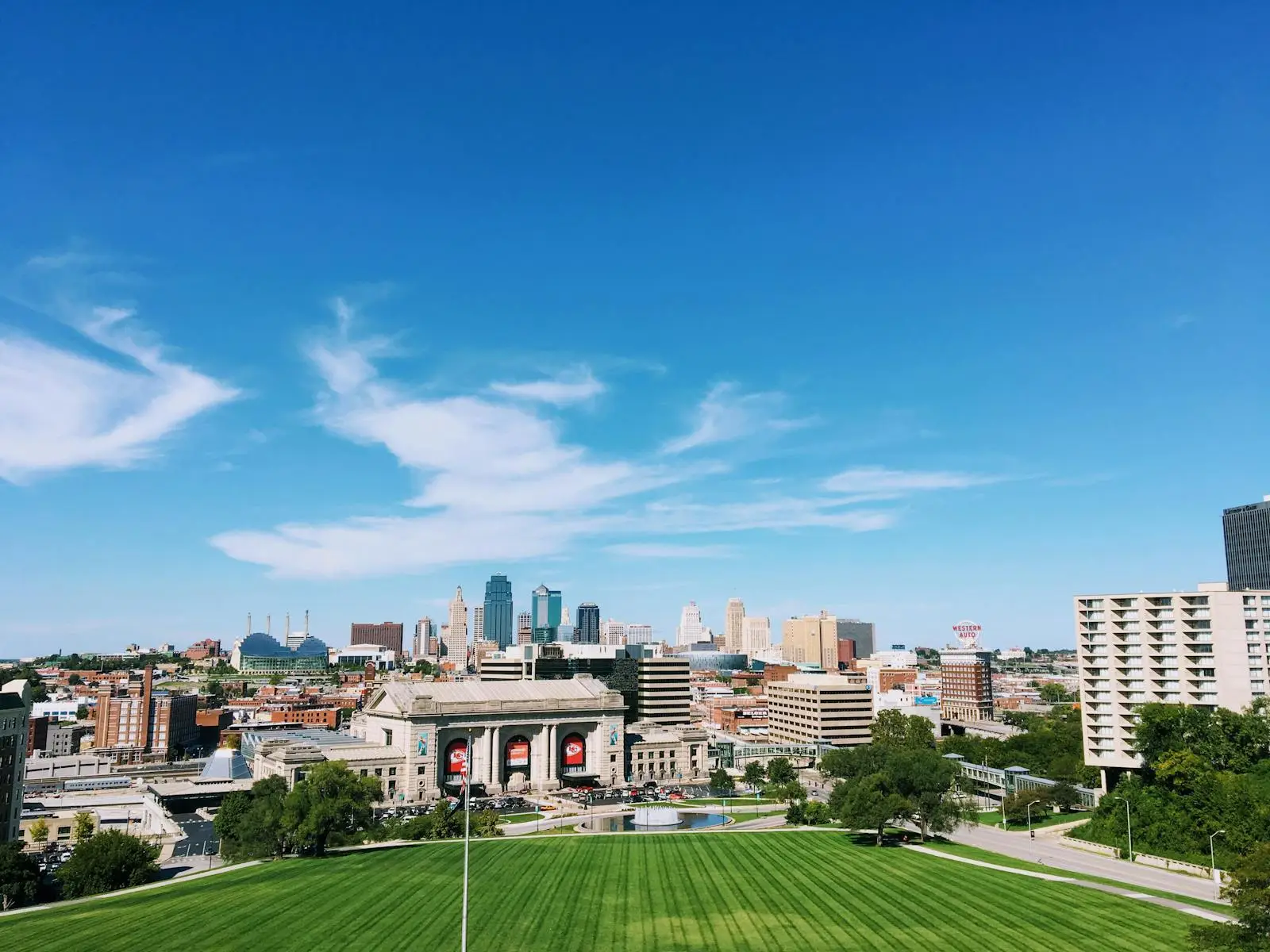 Wide-angle shot of Kansas City's skyline with clear blue skies and vibrant green foreground.